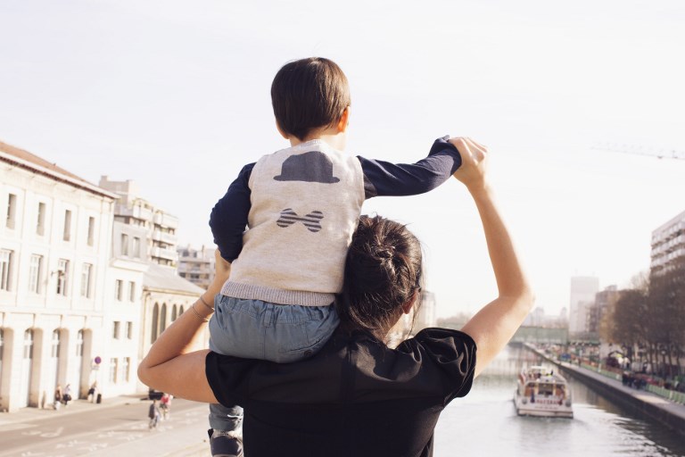 Mother carrying little boy on shoulder, looking at view together