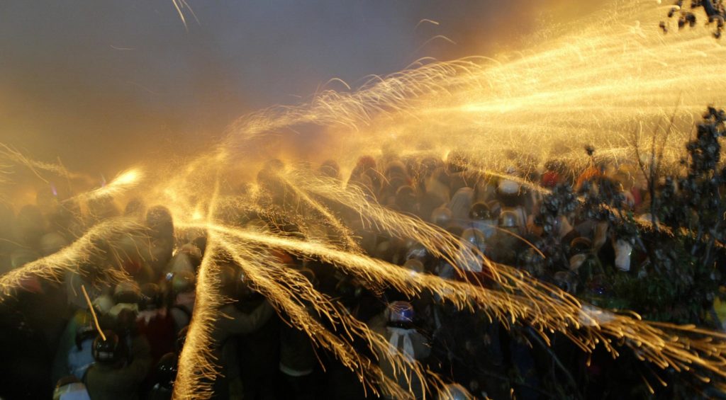 --FILE--Bottle rockets explode and spray fire sparks over visitors during the Yanshui Beehive Rockets Festival in Yanshui District, Tainan city, Taiwan, 27 February 2010.

The Yanshui Beehive Rockets Festival is one of the oldest folk festivals in Taiwan and the third largest in the world. It has been celebrated for over 180 years in the southern district of Yanshui. Its origins date back to 1885, when a cholera epidemic had gripped the district. Due to primitive medical facilities, the disease consumed thousands of victims. Locals lived in a state of fear and prayed to Guan Di, the god of war, to save them. The Beehive Rocket is a multiple launcher of bottle rockets. Thousands of bottle rockets are arranged in rows in an iron-and-wooden framework that looks like a beehive. When the contraption is ignited, the rockets shoot out rapidly in all directions. A deafening, bee-like buzzing sound fills the air. The dazzling explosives whiz and whirl across the sky and into the crowds of dancing people surrounding the beehive. To protect themselves from injuries, locals don heavy clothing, protective gloves and helmets with a full visor. Some also wear a towel around their neck to avoid a stray rocket somehow entering the helmet. Even so, people have been injured in the past. Locals believe in getting bombed by as many firecrackers as possible for good luck in the coming year. Visitors from all over the nation and even foreign tourists crowd at the Yanshui Wu temple well ahead of time, to find a good spot before the Beehive Festival starts. It begins at 6:00 pm and goes on until 5:00 am the following morning.