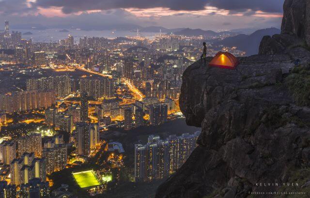 Kelvin在飛鵝山拍攝的這張照片，以城市的高樓及山崖上的營幕作對比，為他贏得2015國家地理攝影大賽冠軍。