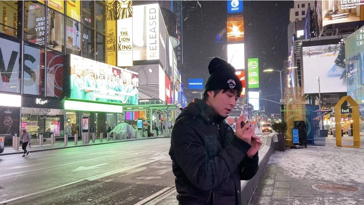 在白雪紛飛的紐約街頭，Leo即興吹奏口琴。他覺得來到美國讀音樂是把以前的夢想成真。