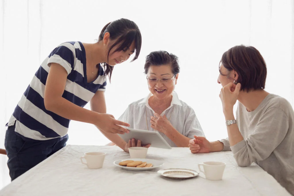 Teenage girl showing tablet to mother and grandmother (Photo by Takahiro Igarashi / Image Source / Image Source via AFP)